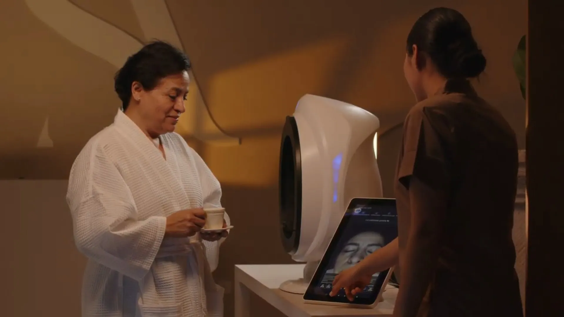 A guest in a robe with her tea reviews the skin analysis on screen with a Santina therapist