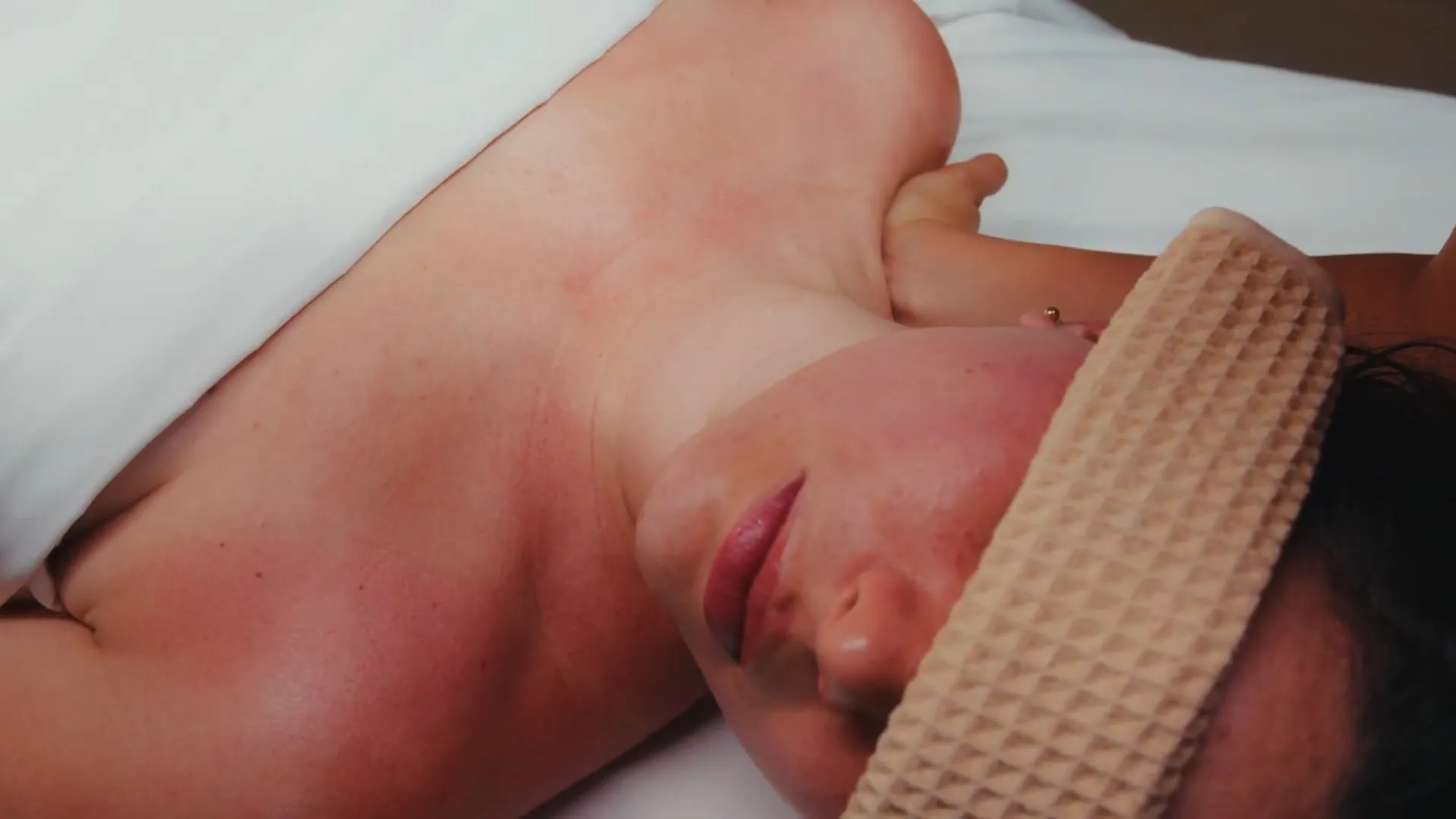 A guest rests with a waffle eye mask on a white pillow
