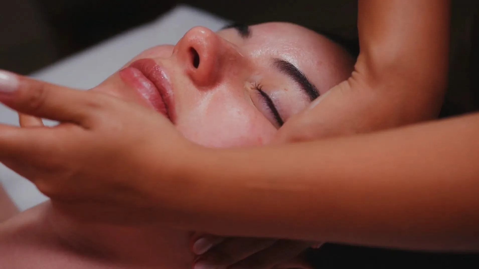 Facial massage in low light, the profile lit softly