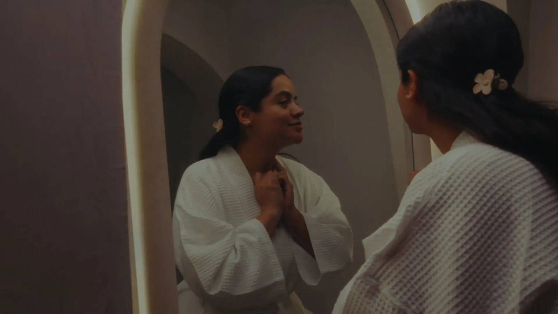 Two guests in robes talk under an arch of the house